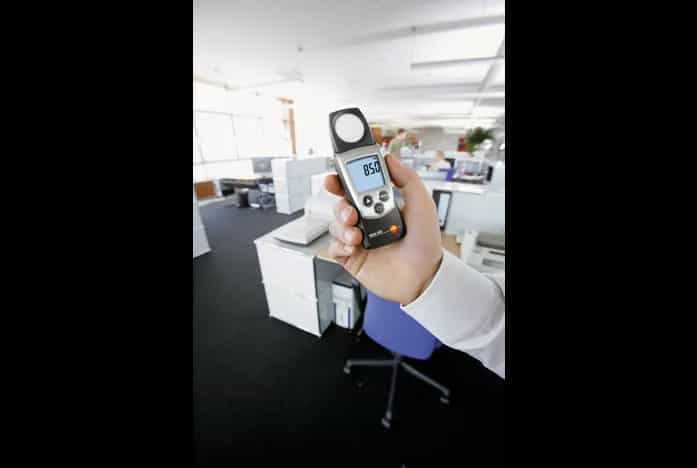 Luksomierz Testo 540 trzymany w dłoni podczas pomiaru natężenia oświetlenia w biurze (miniatura)
