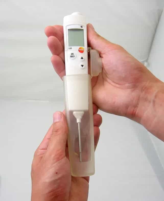 Dłonie trzymające termometr Testo 106 z założoną osłoną ochronną TopSafe (miniatura)