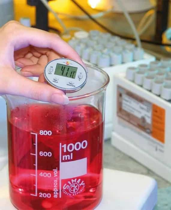Termometr Testo zanurzony w czerwonej cieczy w zlewce laboratoryjnej 1000 ml — pomiar temperatury cieczy (miniatura)