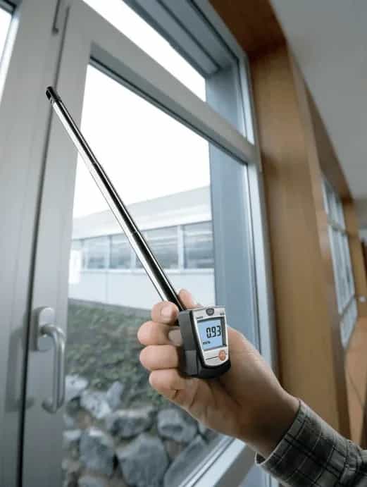 Anemometr Testo 405 z wysuniętym teleskopem podczas wykrywania nieszczelności przy oknie (miniatura)