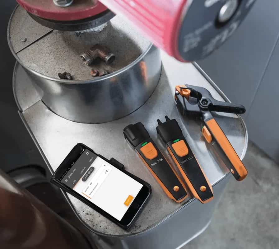 Zestaw mierników Testo z aplikacją Smart App wyświetlaną na smartfonie przy urządzeniu grzewczym (miniatura)