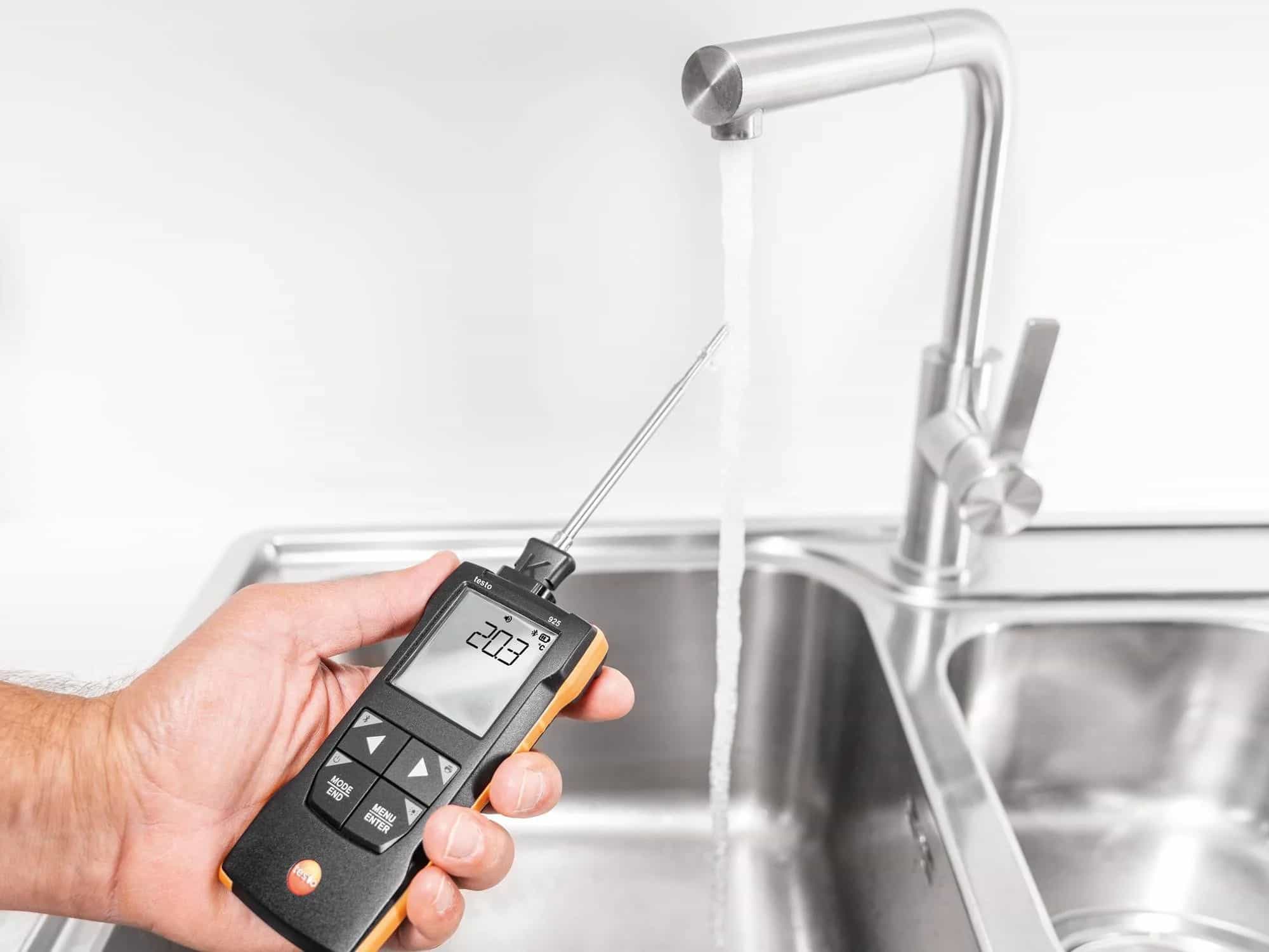 Ręka trzymająca termometr Testo 925 mierzący temperaturę wody przy kranie — widoczny odczyt 20,3°C na wyświetlaczu (miniatura)