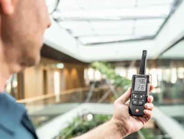 Specjalista trzymający termohigrometr testo 625 podczas kontroli klimatu w hotelu (miniatura)