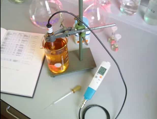 Testo 206-pH3 podłączony do sondy zewnętrznej podczas pomiaru pH w laboratorium — zlewki i statyw w tle (miniatura)