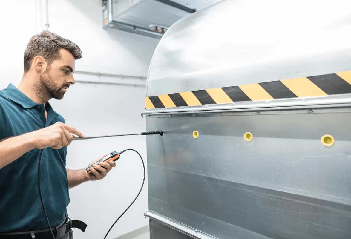 Technik mierzy przepływ w kanale wentylacyjnym sondą teleskopową Testo 440 (miniatura)