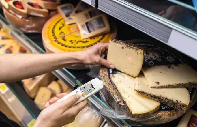 Pracownik supermarketu mierzy pirometrem Testo 826-T2 temperaturę sera w ladzie chłodniczej (miniatura)