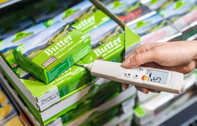 Dłoń pracownika mierzącego temperaturę masła w sklepie spożywczym pirometrem Testo 826-T4 (miniatura)