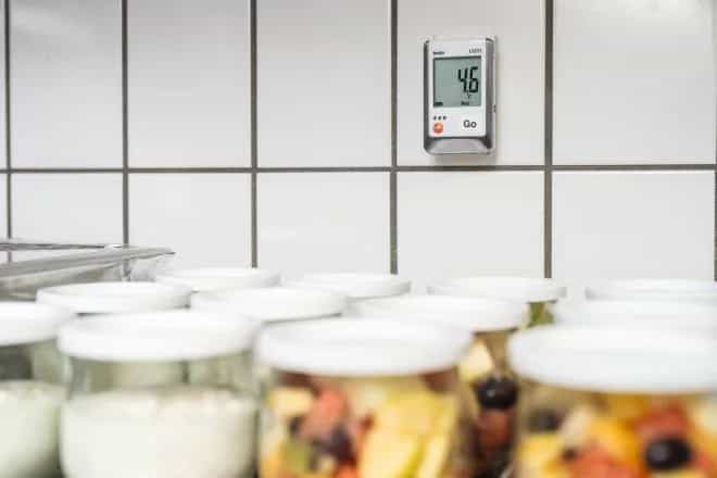Rejestrator Testo 175 T1 zamontowany na ścianie nad zapasami żywności w chłodni gastronomicznej, na wyświetlaczu 4,6°C (miniatura)