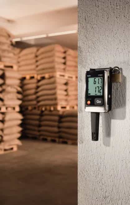 Rejestrator Testo 175 H1 zamontowany na ścianie magazynu z paletami worków, z kłódką zabezpieczającą uchwyt (miniatura)