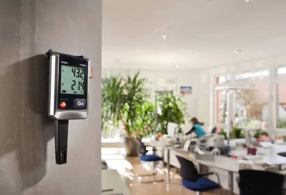 Rejestrator Testo 175 H1 zamontowany na filarze w jasnym pomieszczeniu biurowym, monitorujący temperaturę i wilgotność klimatu wnętrza (miniatura)