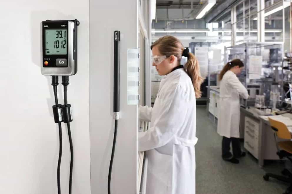 Rejestrator Testo 176 P1 zamontowany na ścianie laboratorium z podłączoną sondą wilgotności podczas monitoringu warunków przechowywania (miniatura)