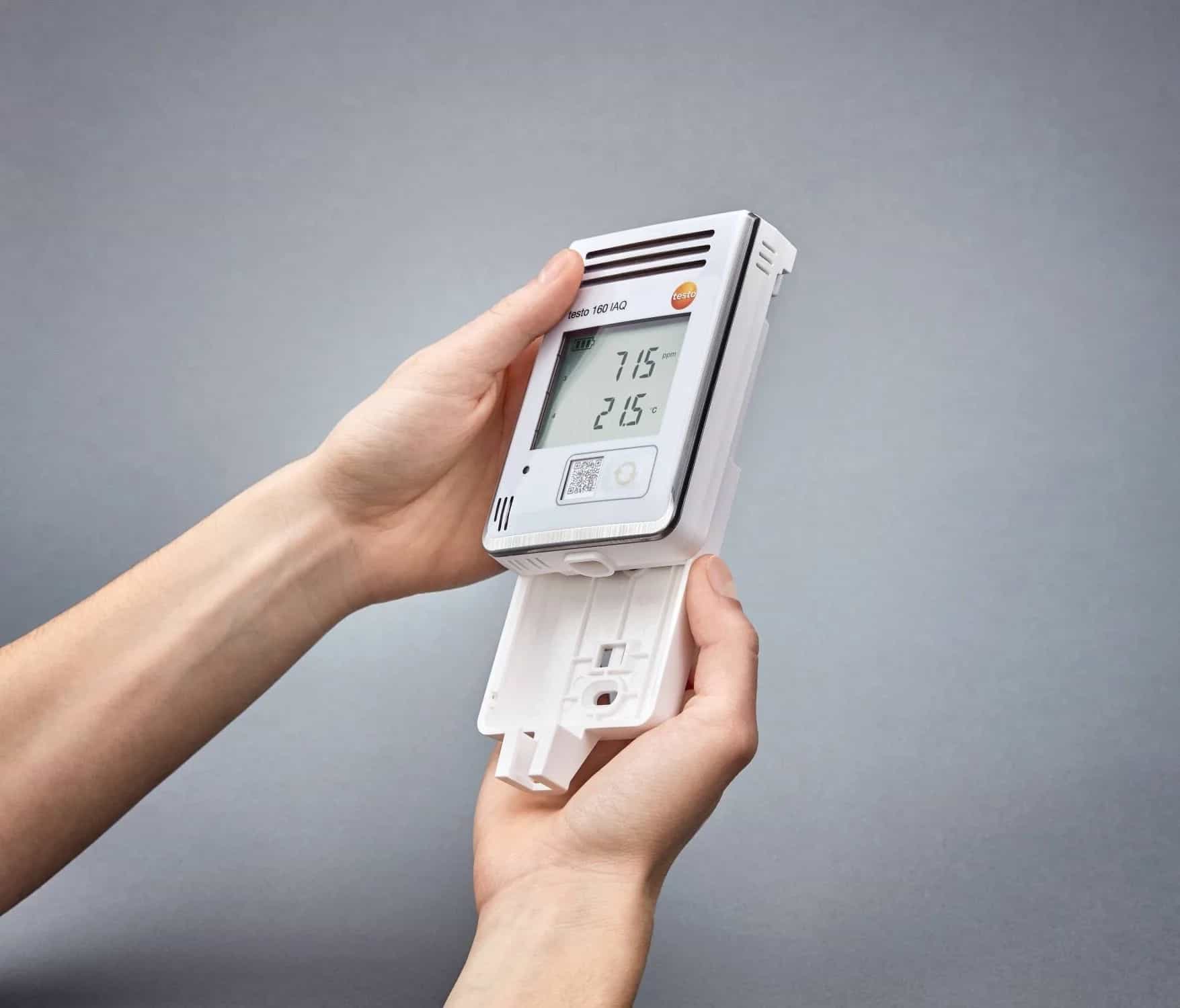 Ręce montujące rejestrator Testo 160 IAQ na uchwycie ściennym (miniatura)