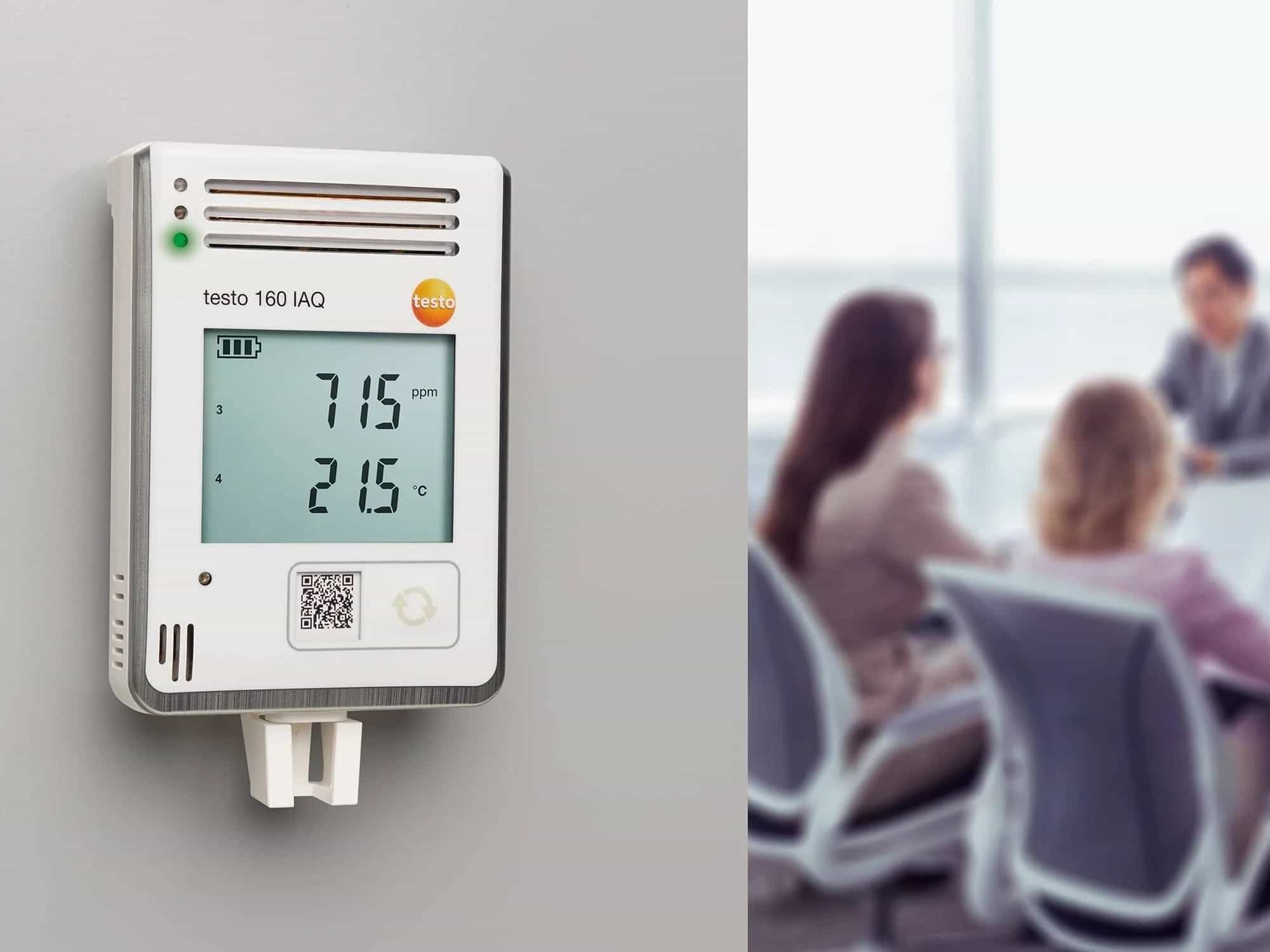 Rejestrator Testo 160 IAQ zamontowany na ścianie w sali konferencyjnej podczas spotkania (miniatura)