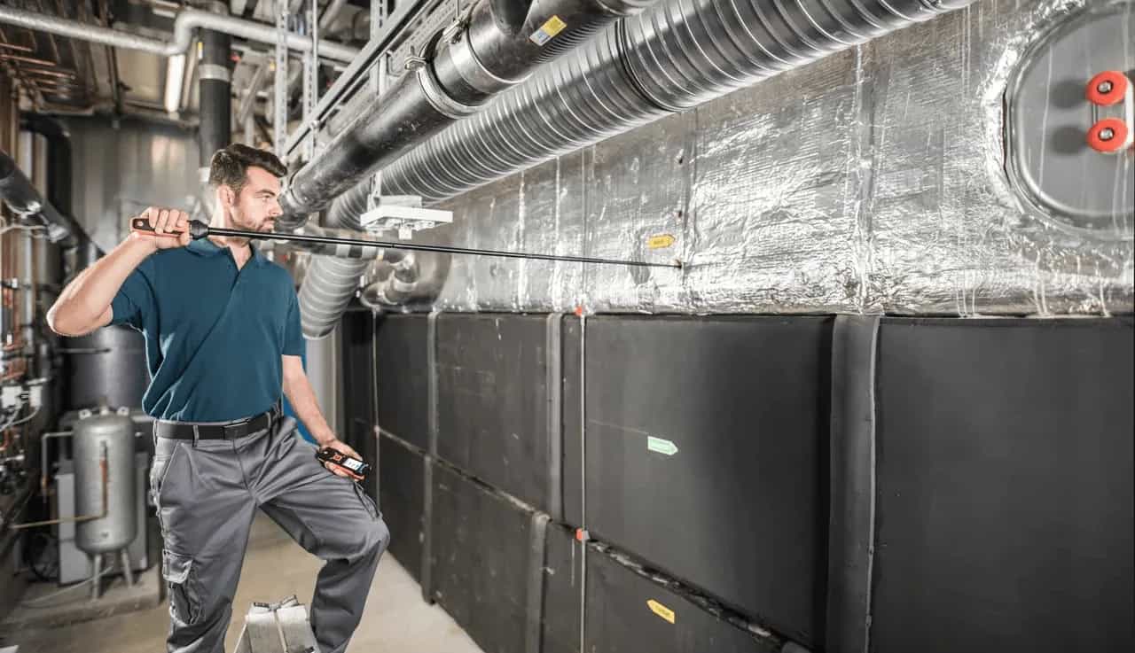 Technik HVAC mierzący przepływ powietrza przy central wentylacyjnej i kanałach w pomieszczeniu technicznym (miniatura)