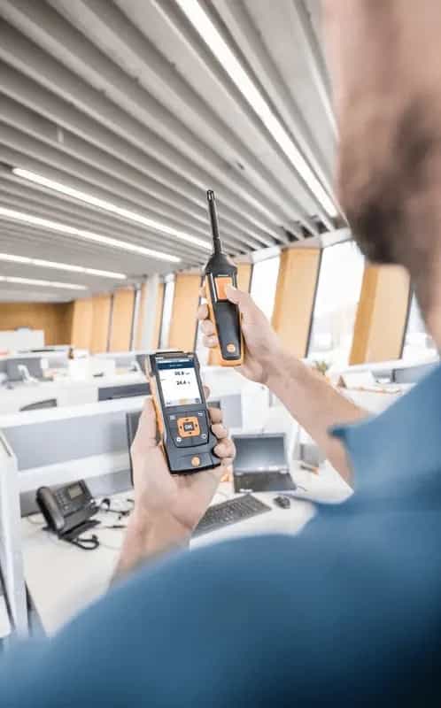 Technik odczytujący wyniki sondy Testo na smartfonie przez aplikację Bluetooth w pomieszczeniu biurowym (miniatura)