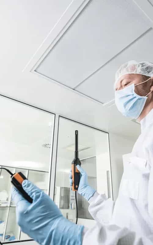 Technik w czystym pomieszczeniu produkcyjnym wykonujący pomiar wilgotności sondą Testo z łącznością Bluetooth (miniatura)