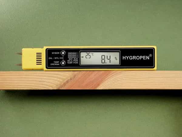 Wilgotnościomierz HYGROPEN leżący na desce drewnianej — wynik pomiaru 8,4% wilgotności drewna na wyświetlaczu LCD (miniatura)