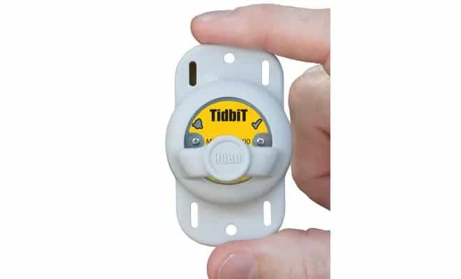 Rejestrator HOBO TidbiT MX2203 trzymany w dłoni podczas odczytu danych przez Bluetooth (miniatura)