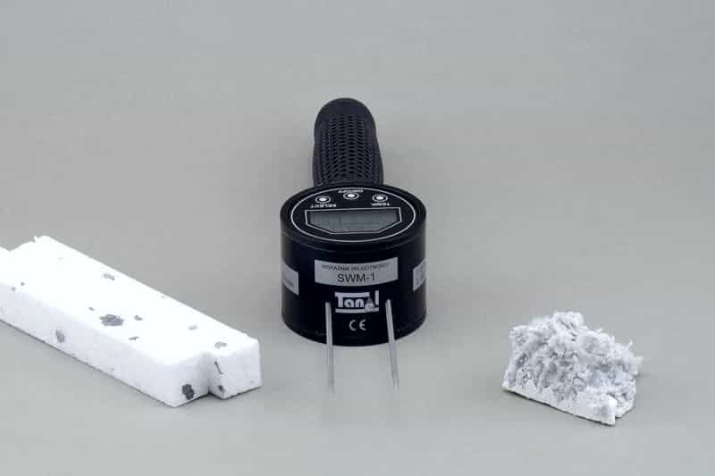 Wilgotnościomierz SWM-1 stojący pionowo z próbkami styropianu i wełny mineralnej po bokach (miniatura)