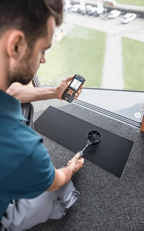 Pomiar prędkości powietrza sondą wiatraczkową Testo z łącznością Bluetooth przy kratce wentylacyjnej