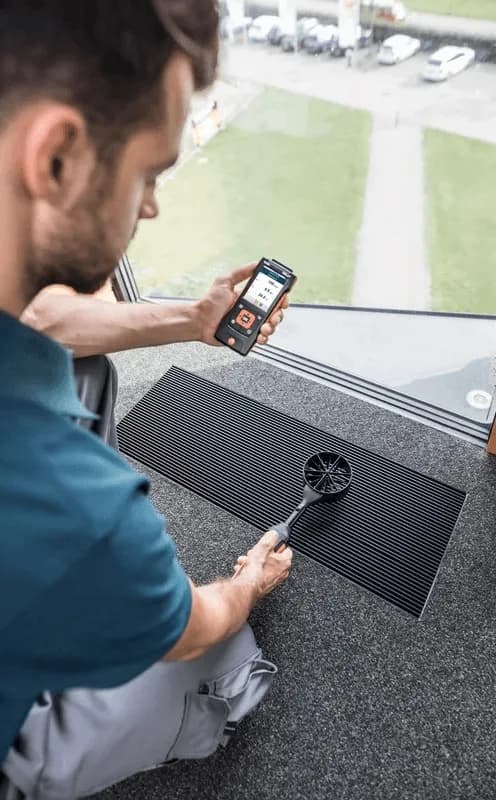 Technik HVAC wykonuje pomiary miernikiem Testo 440 dP przy instalacji wentylacyjnej w maszynowni
