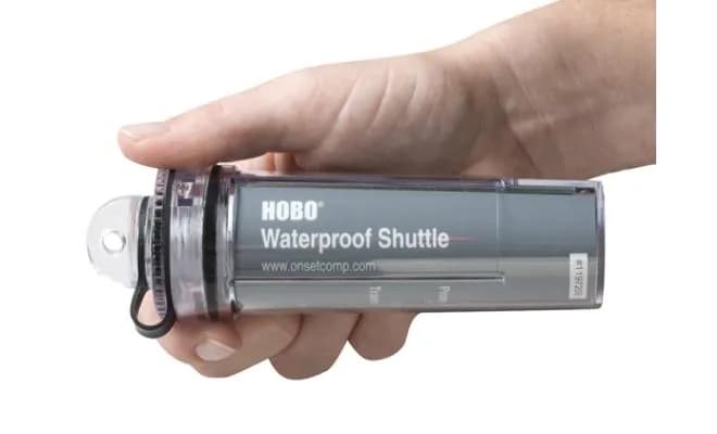 Dłoń trzymająca wodoodporny interfejs HOBO Waterproof Shuttle — widok urządzenia w terenie