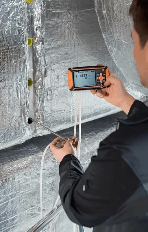 Technik mierzy przepływ manometrem Testo 420 na izolowanej instalacji wentylacyjnej HVAC (miniatura)