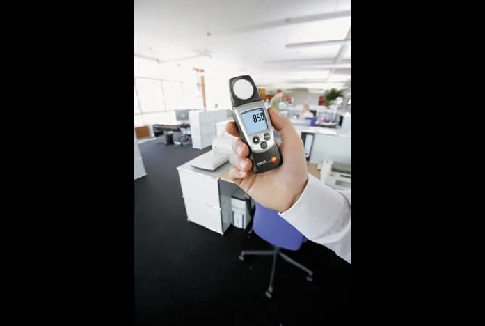 Luksomierz Testo 540 trzymany w dłoni podczas pomiaru natężenia oświetlenia w biurze (miniatura)