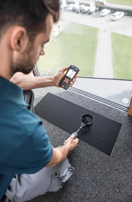 Technik wykonujący pomiar miernikiem Testo 440 w terenie podczas prac kontrolnych (miniatura)