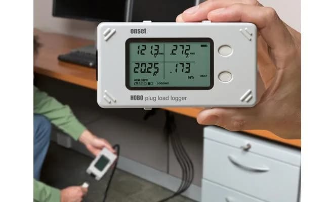 HOBO Plug Load UX120-018 trzymany w dłoni podczas pomiaru zużycia energii w biurze (miniatura)