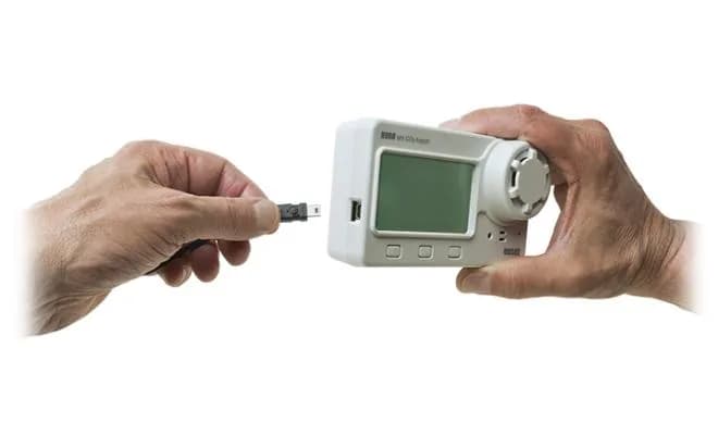 Dwie dłonie podłączające kabel USB do rejestratora HOBO MX1102A