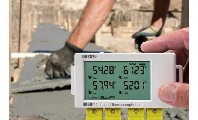 Rejestrator HOBO UX120-014M w dłoni podczas pomiaru temperatury betonu na placu budowy