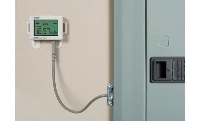 Rejestrator HOBO UX90-001 zamontowany na ścianie, podłączony kablem do rozdzielnicy elektrycznej