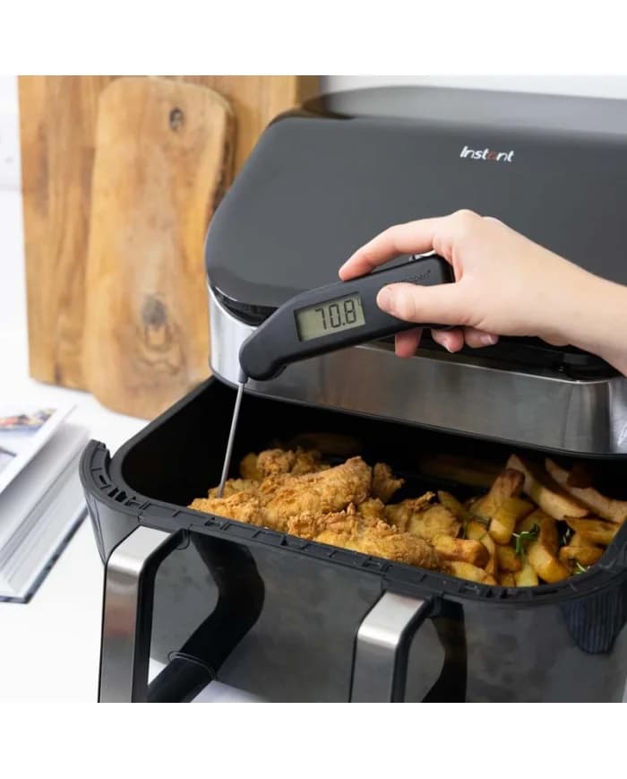 Dłoń mierzy termometrem Thermapen Classic temperaturę panierowanego mięsa i frytek w koszu frytkownicy beztłuszczowej